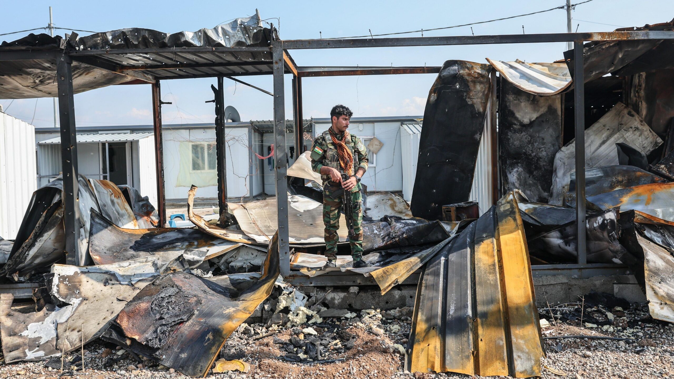 A member of Kurdistan Freedom Party stands next to damaged containers at their military base in Irbil, Iraq, after Iranian drone attack in March