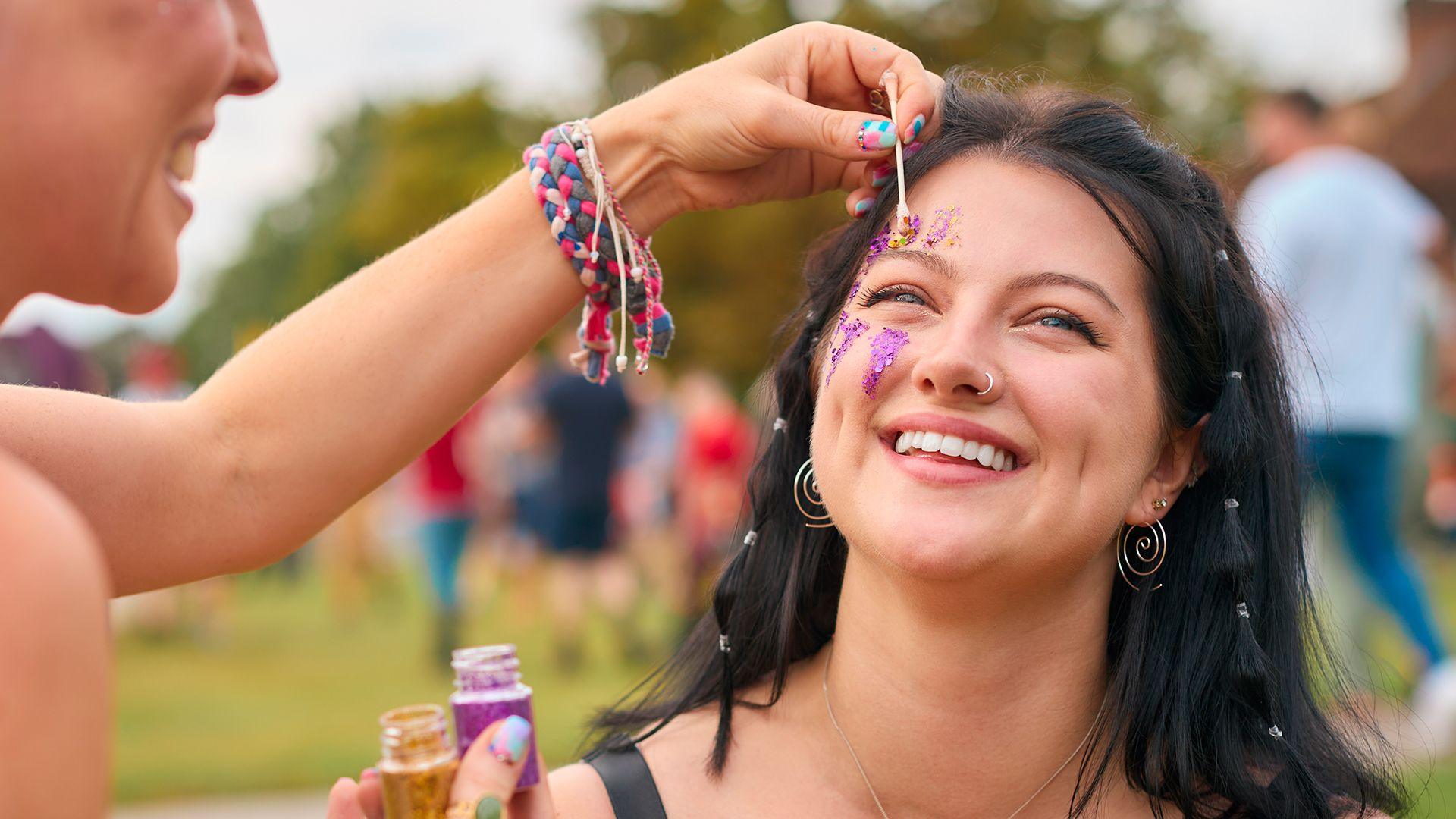 A woman applying bright make-up at a festival