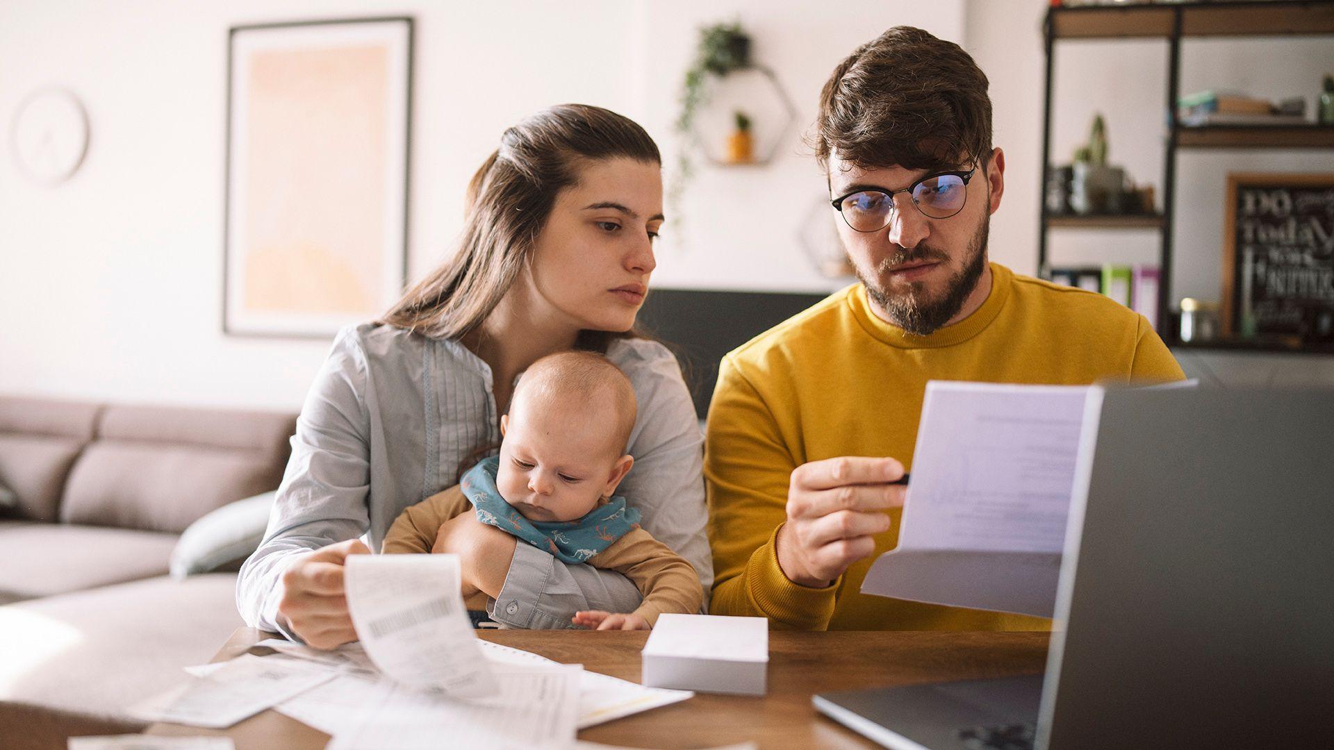 Man, woman and baby sit at a table examining a household bill
