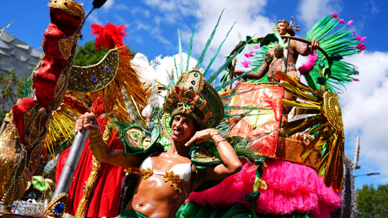 A group of performers in ornate beaded costumes stand on a parade float.