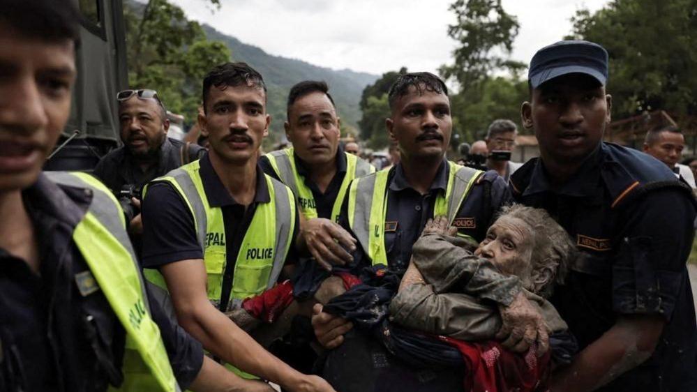 Police officers carrying an elderly woman who survived the flash flood at Trishuli in Nuwakot district of Nepal