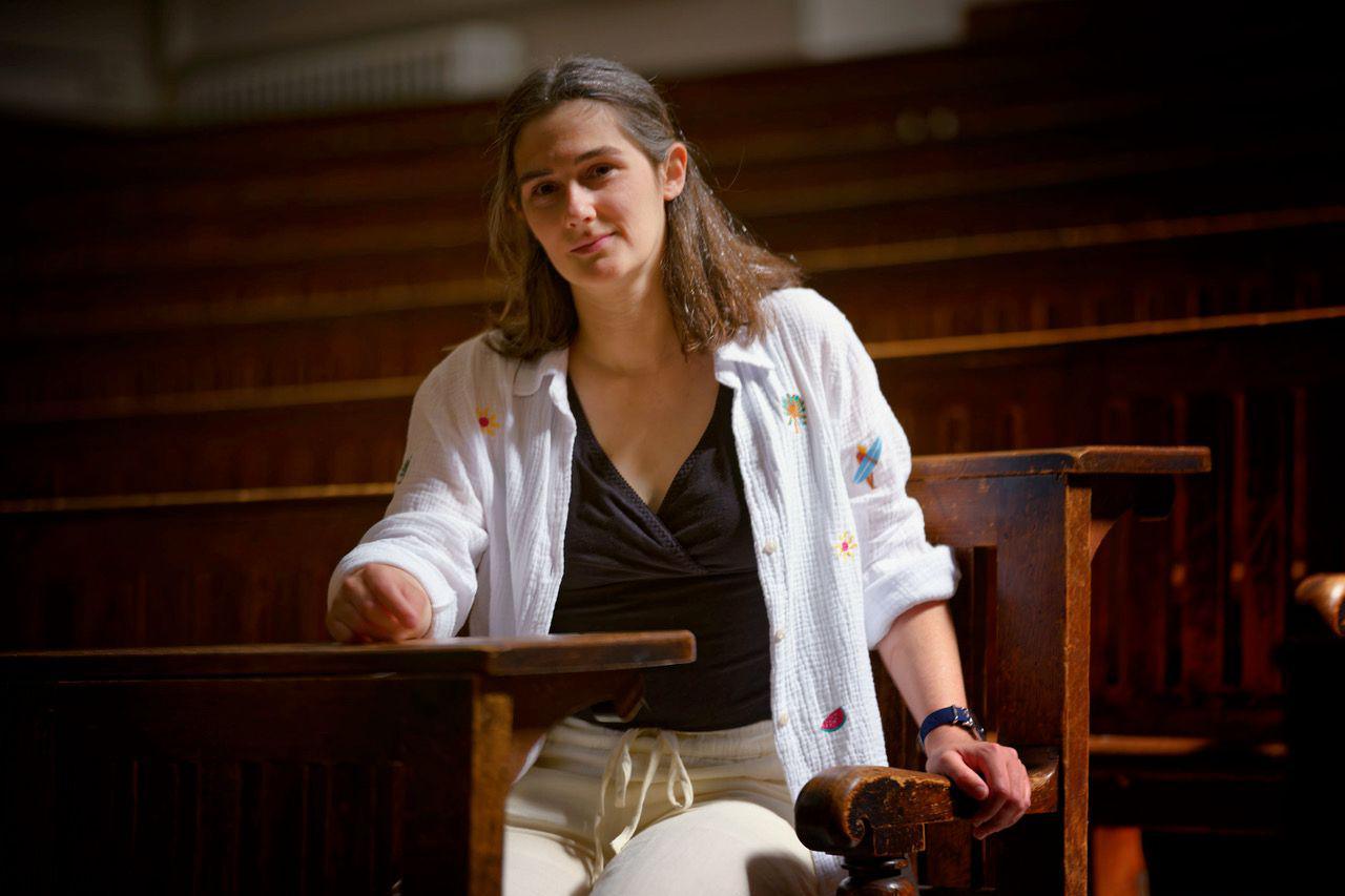 Amanda Cole sits on one of the lecture theatre benches at Cambridge University