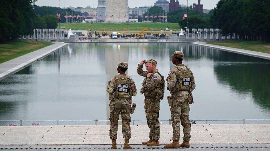 Three members of the National Guard stand in front of the Reflecting Pool