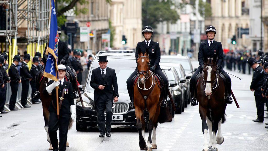 Police officers on horses lead the funeral cortege for PC Andrew Harper as officers line the street
