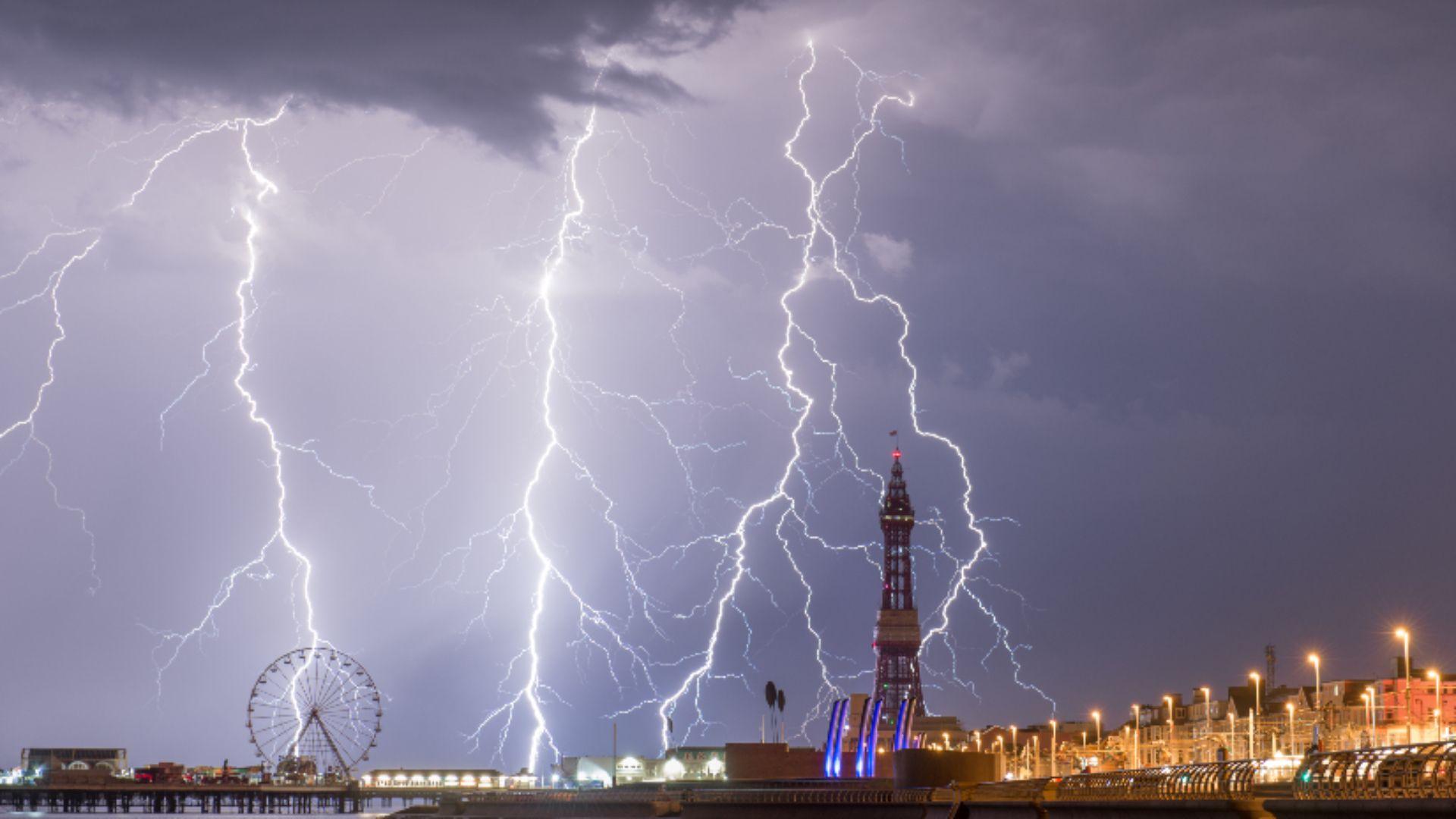 Blackpool tower surrounded by strikes of lighting at night.