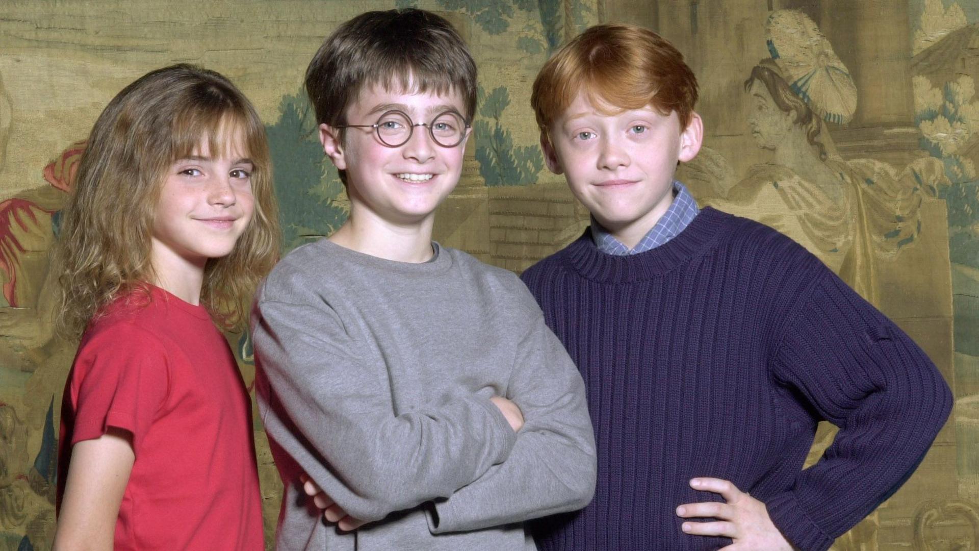 The young Emma Watson, Daniel Radcliffe and Rupert Grint standing and posing together and smiling
