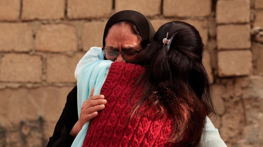 Woman being comforted at site of Gul plaza fire
