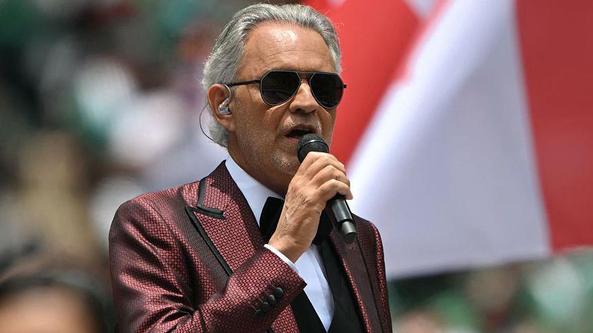 Bocelli wearing a red patterned suit with a tuxedo.