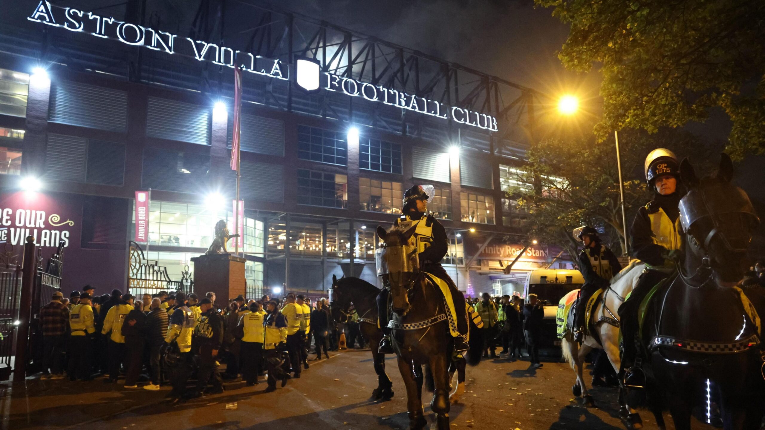 Mounted police officers wearing high-vis jackets over uniform stand outside Aston Villa Football ground. Behind them many other officers wearing bright yellow jackets can be seen