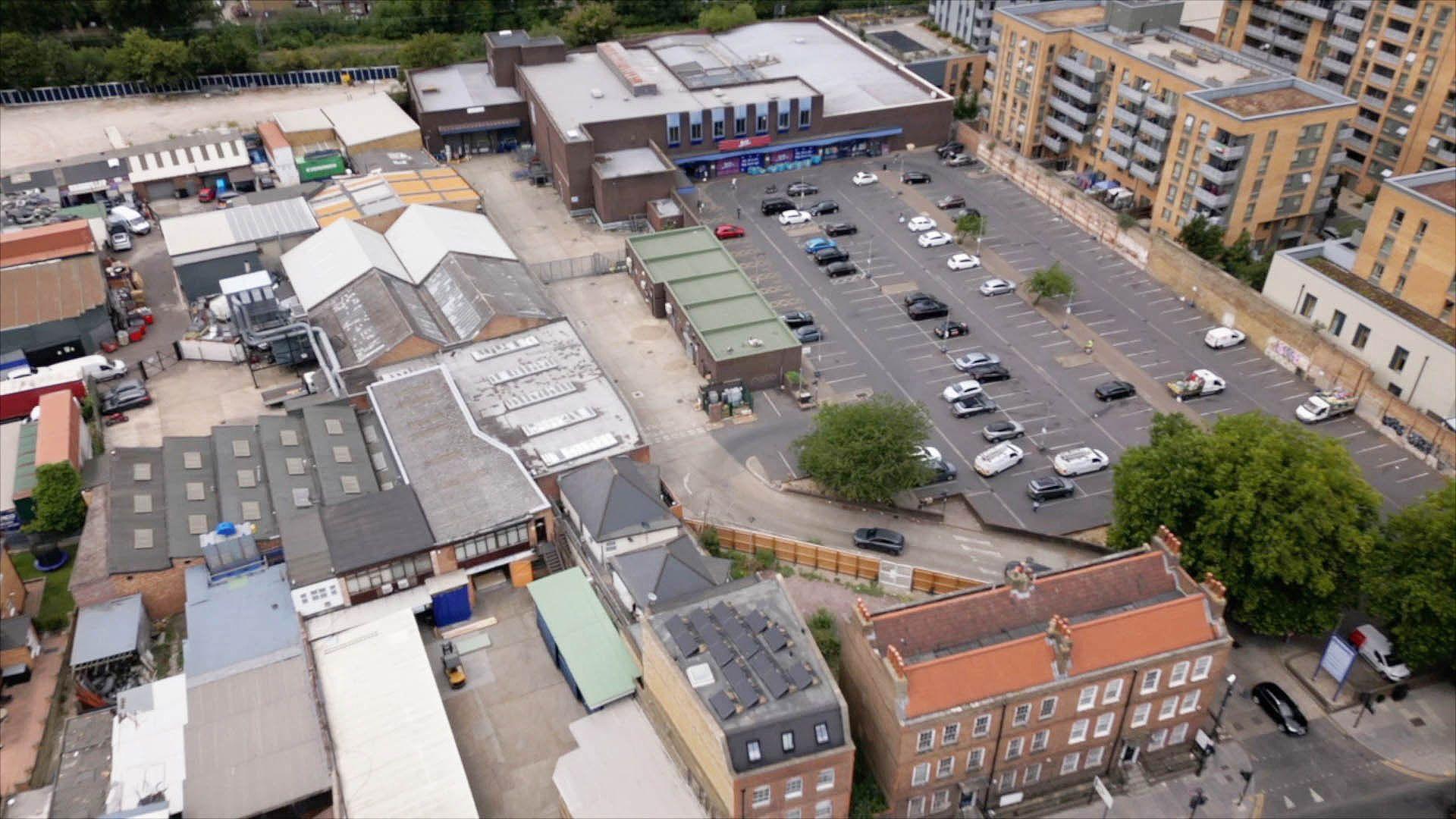 A view of the B&M store car park in Tottenham, north London. There are industrial units to the left of the car park and modern flats to the right.