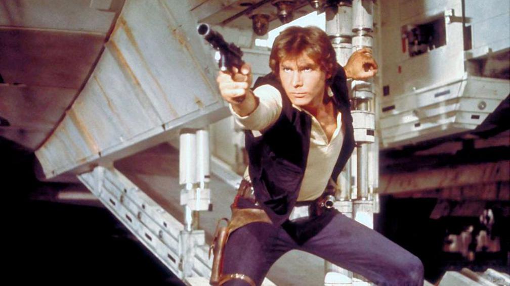 Han Solo in a screen grab from Star Wars. He has a phaser in hand about to shoot and is holding the open exit ramp to the millennium falcon