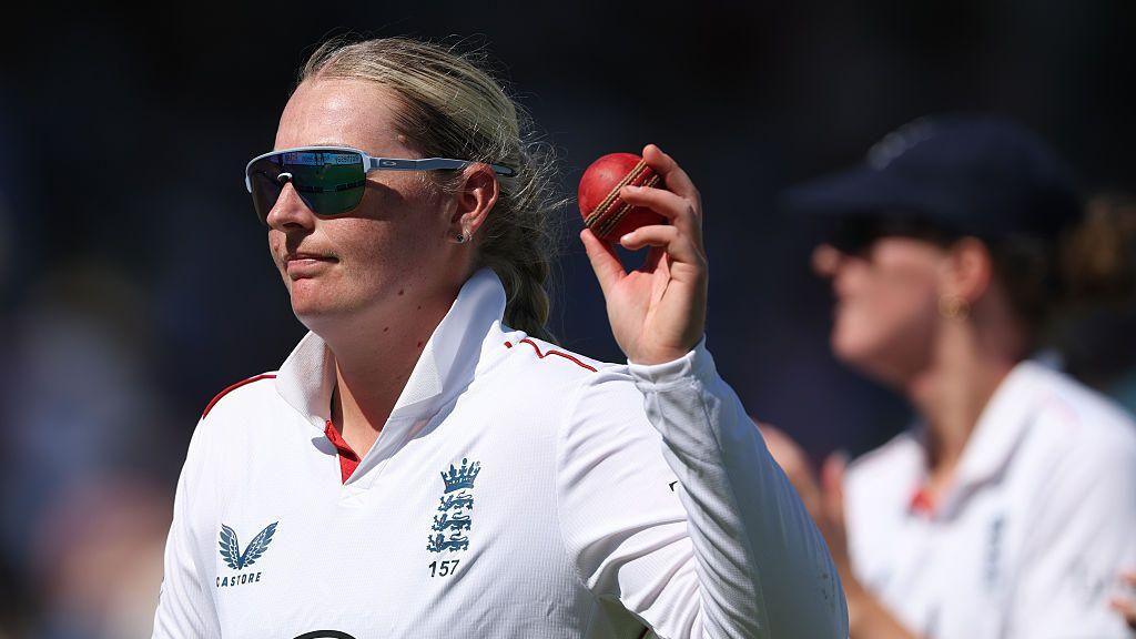 Sophie Ecclestone raises the match ball after taking five wickets v India