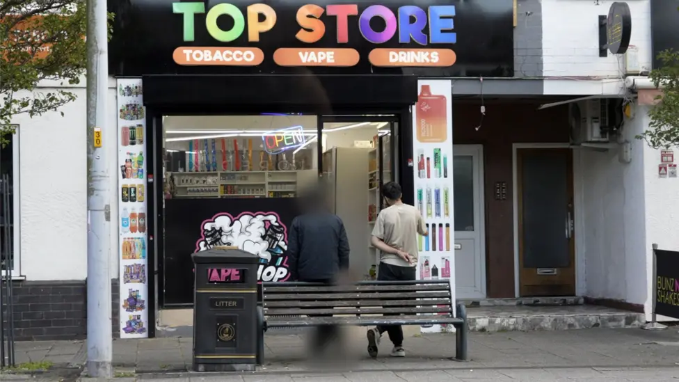 Two men stand outside a vape shop called Top Store