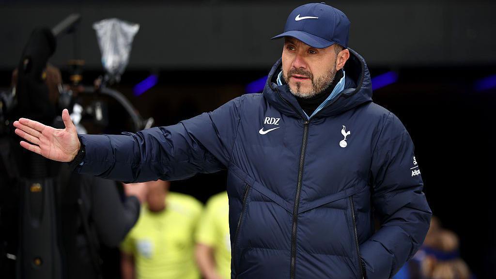 Roberto de Zerbi gestures with his right arm while managing Tottenham