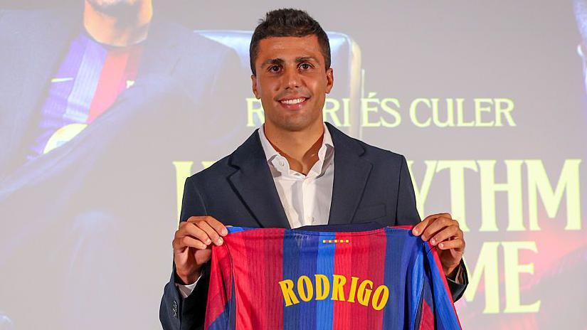 Rodri smiling and holding a Barcelona top