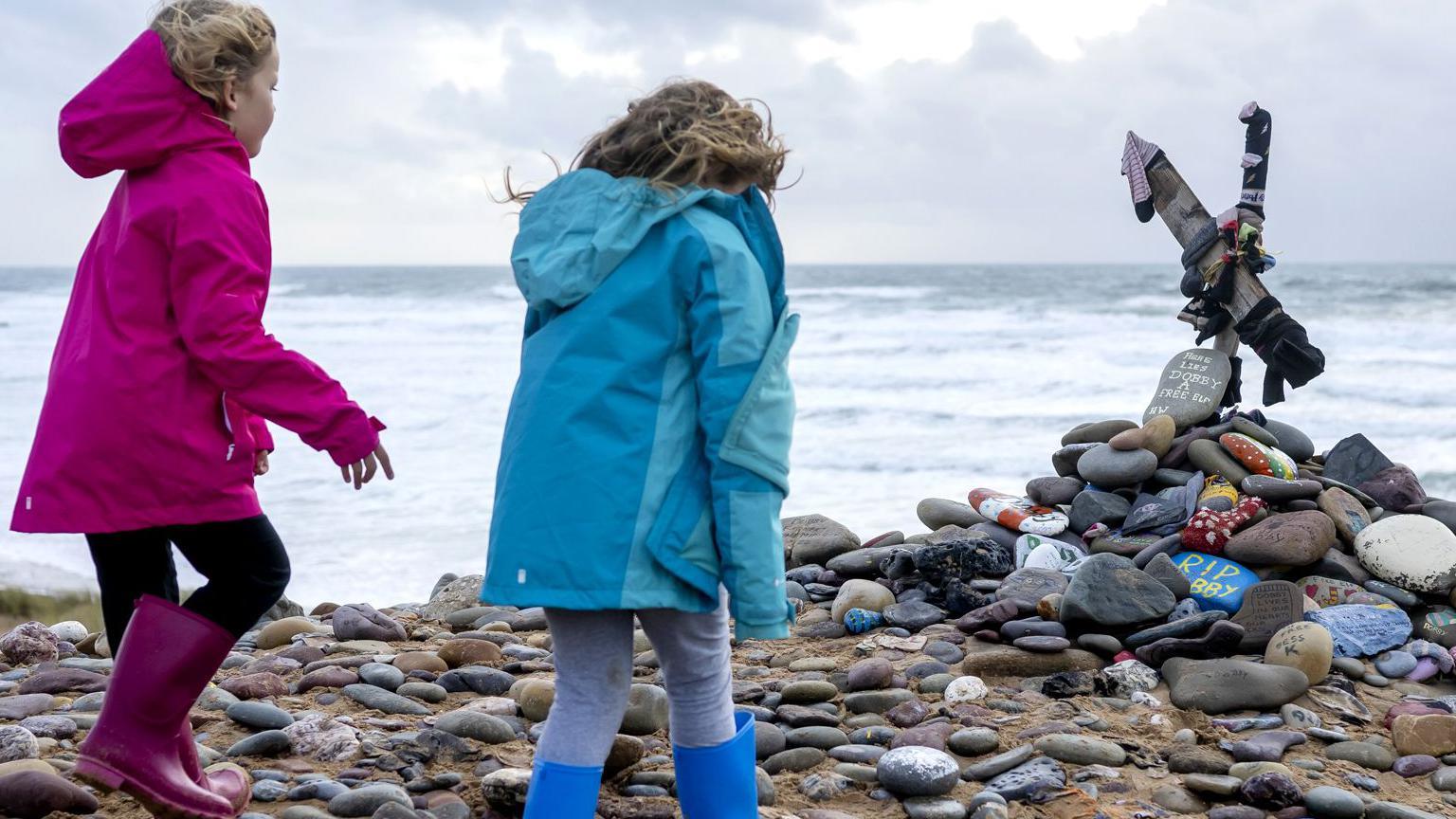 Children look at a memorial for Dobby, a fictional house elf from the Harry Potter fantasy novels and films, at Freshwater West beach on November 6, 2022 in Castlemartin, United Kingdom.