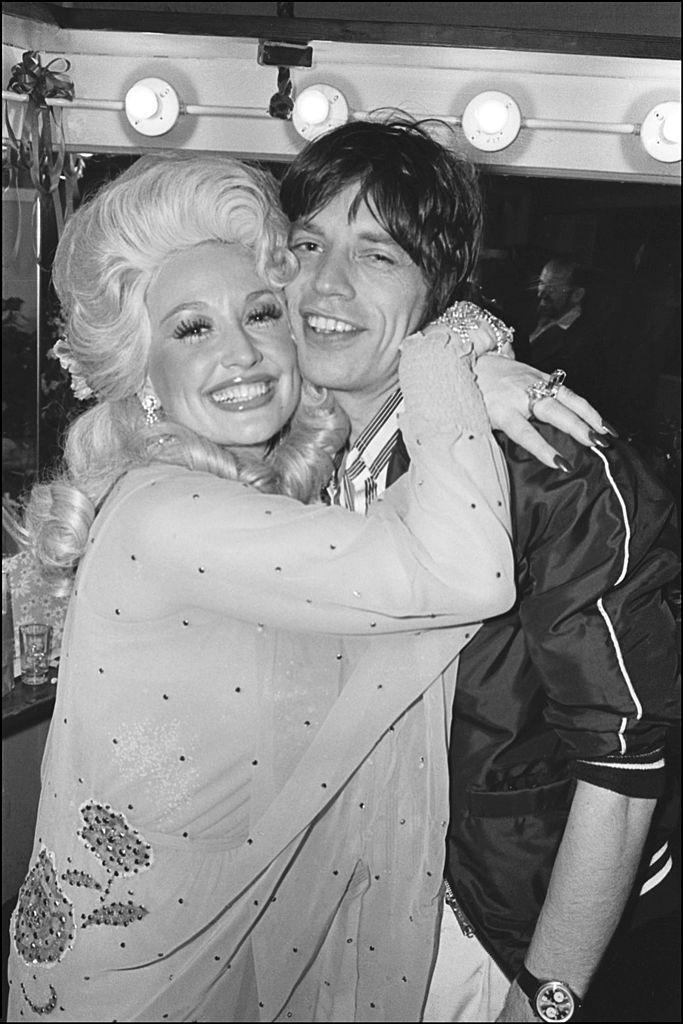 After her performance at the Bottom Line, American Country musician Dolly Parton is seen hugging British rocker Mick Jagger backstage, New York, New York, May 14, 1977