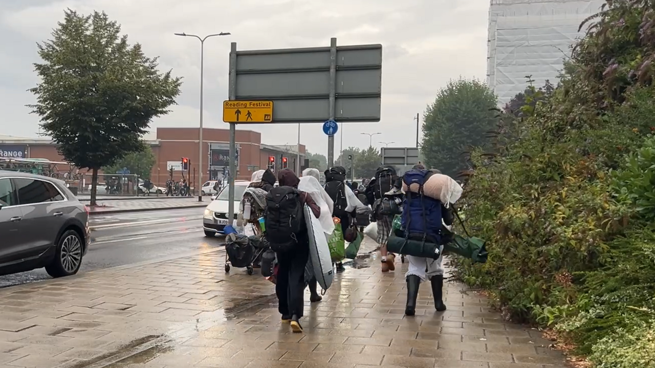 People walking, with their backs to the camera, to the festival site, close to Reading station, with The Range store on the left of the picture.