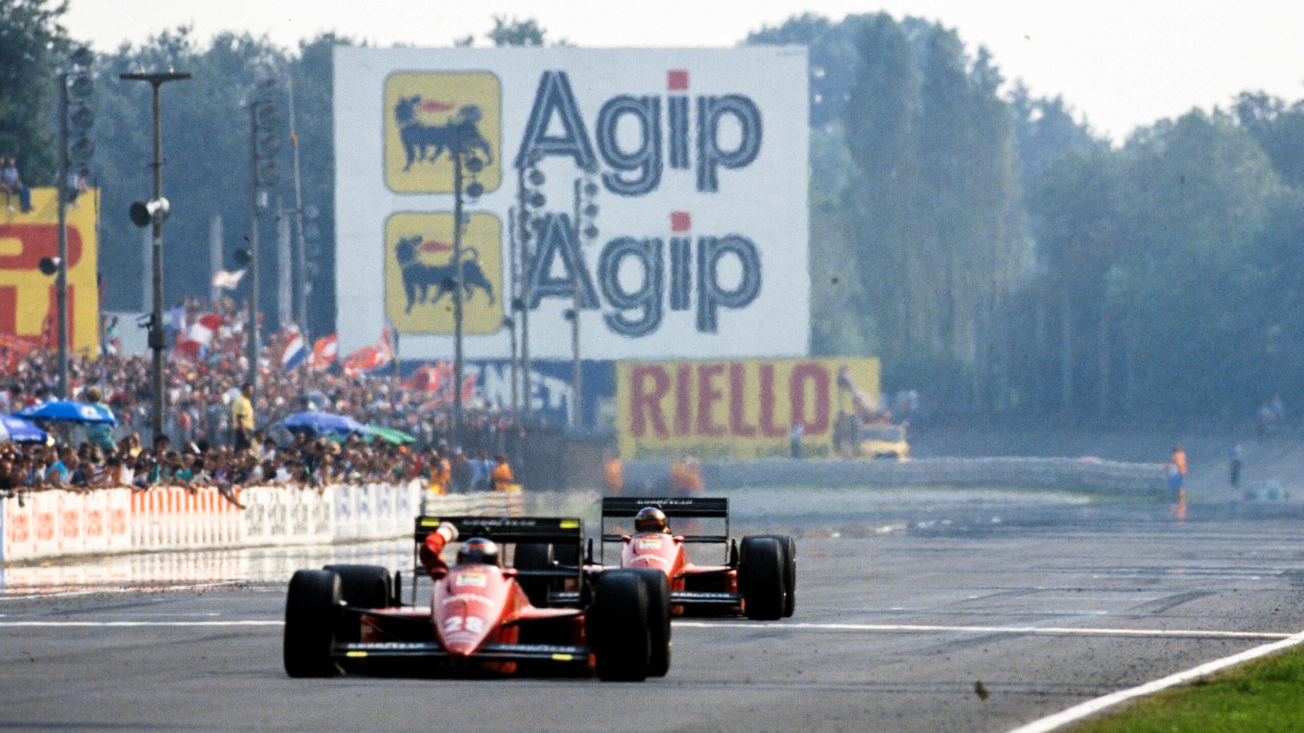 Race winner Gerhard Berger clenches his fist in celebration after crossing the line to win the 1988 Italian Grand Prix for Ferrari. His team-mate Michele Alberto, in second place, is in the process of crossing the line just behind Berger