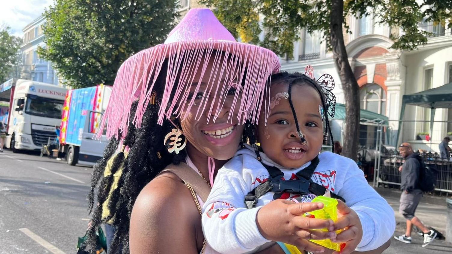 Mum and baby hug on the roadside in costumes for carnival