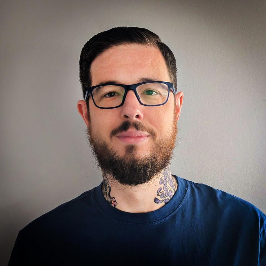 A headshot of Dr Michael Rees who is wearing a black t-shirt and standing against a white background.