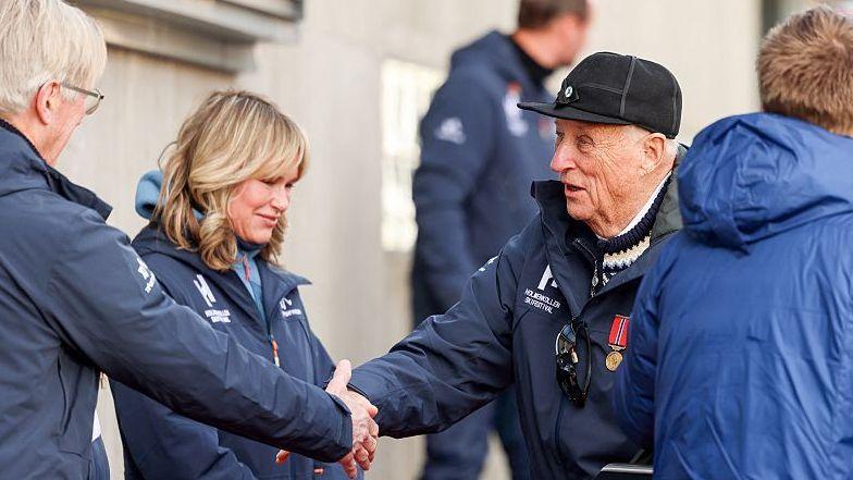 King Harald V of Norway (R) is greeted by Oslo's Mayor Anne Lindboe (C) upon arrival in Holmenkollen, near Oslo, on March 15, 2025, during the FIS Nordic Combined World Cup
