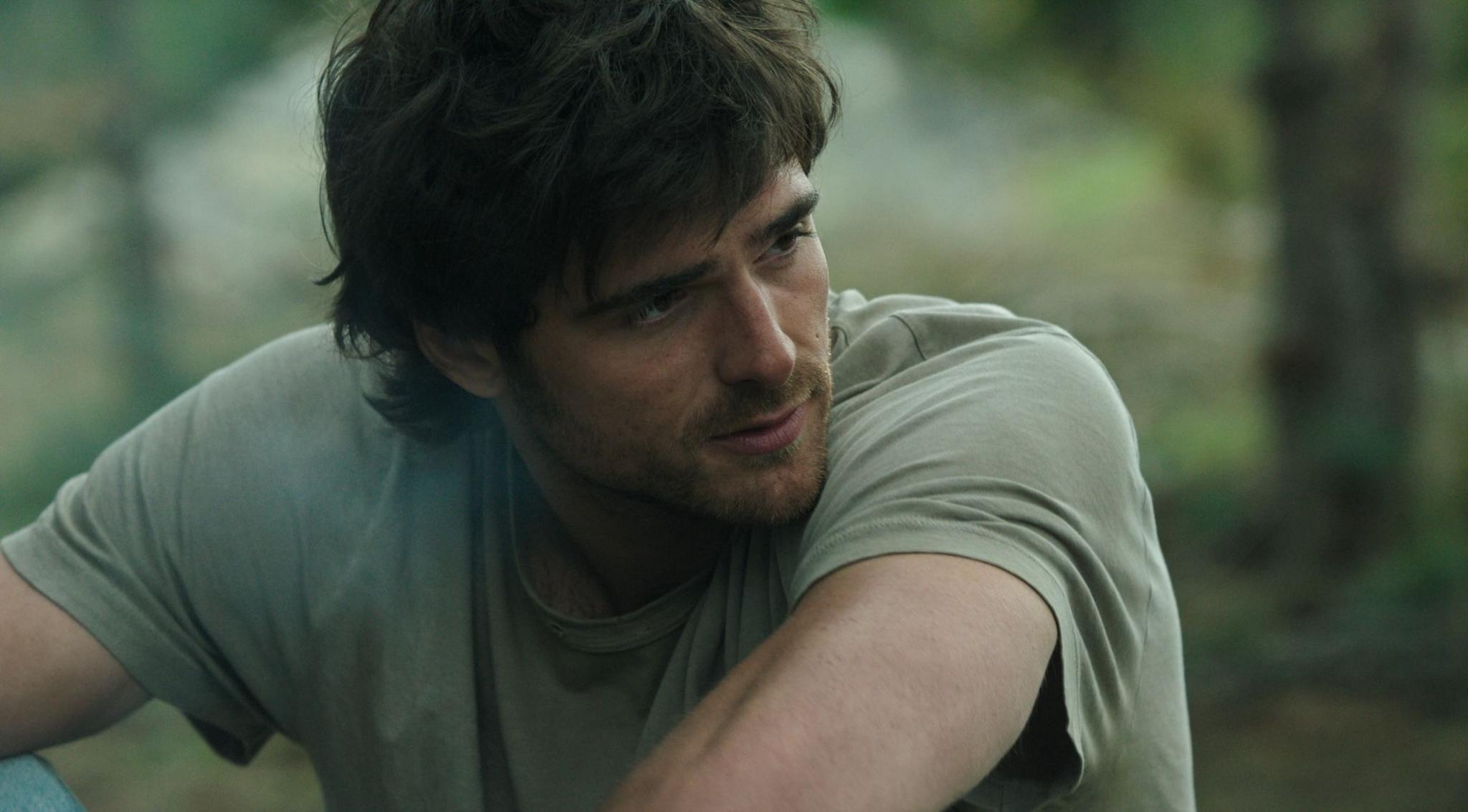 Jacob Elordi appears dishevelled with shaggy hair, a beard and wearing a light green t-shirt.