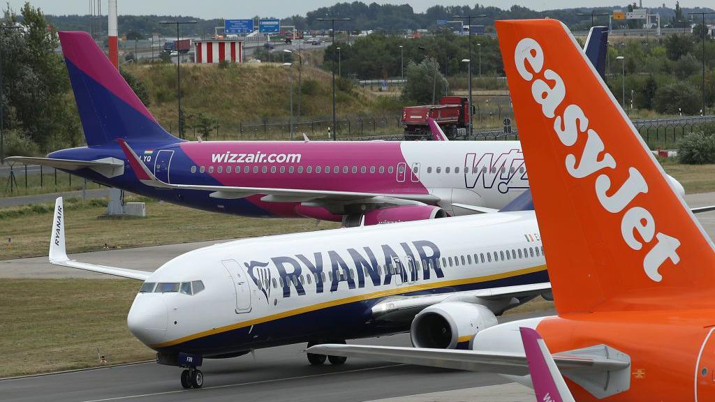 A Wizz Air, Ryanair and Easyjet plane on an airport airfield.