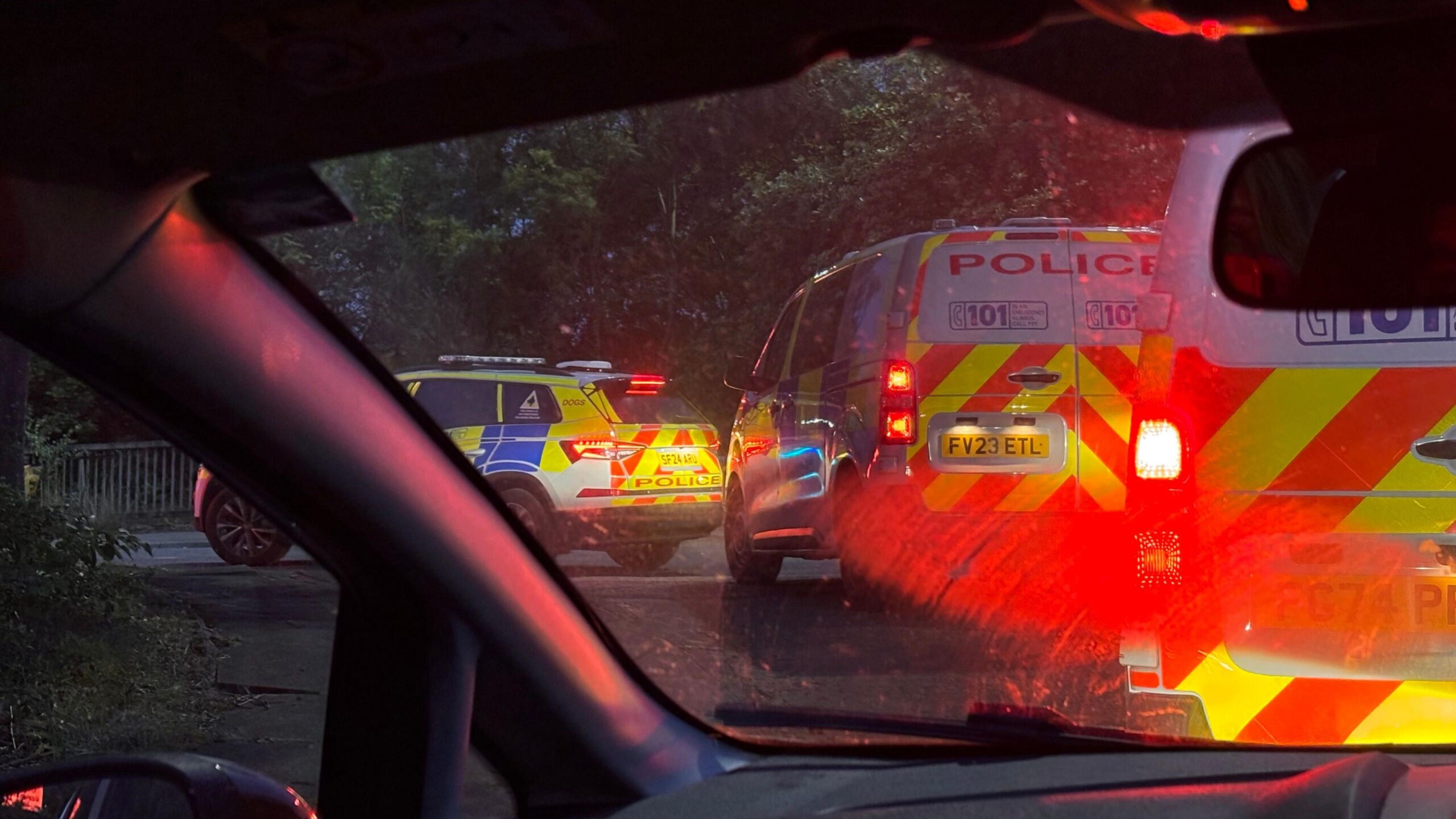 two police vans and a police car photographed from inside a car