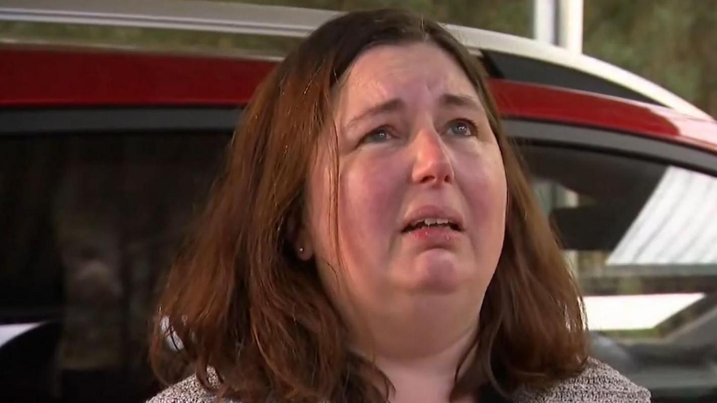 Headshot of Erin Patterson as she looks up while stood in front of a car
