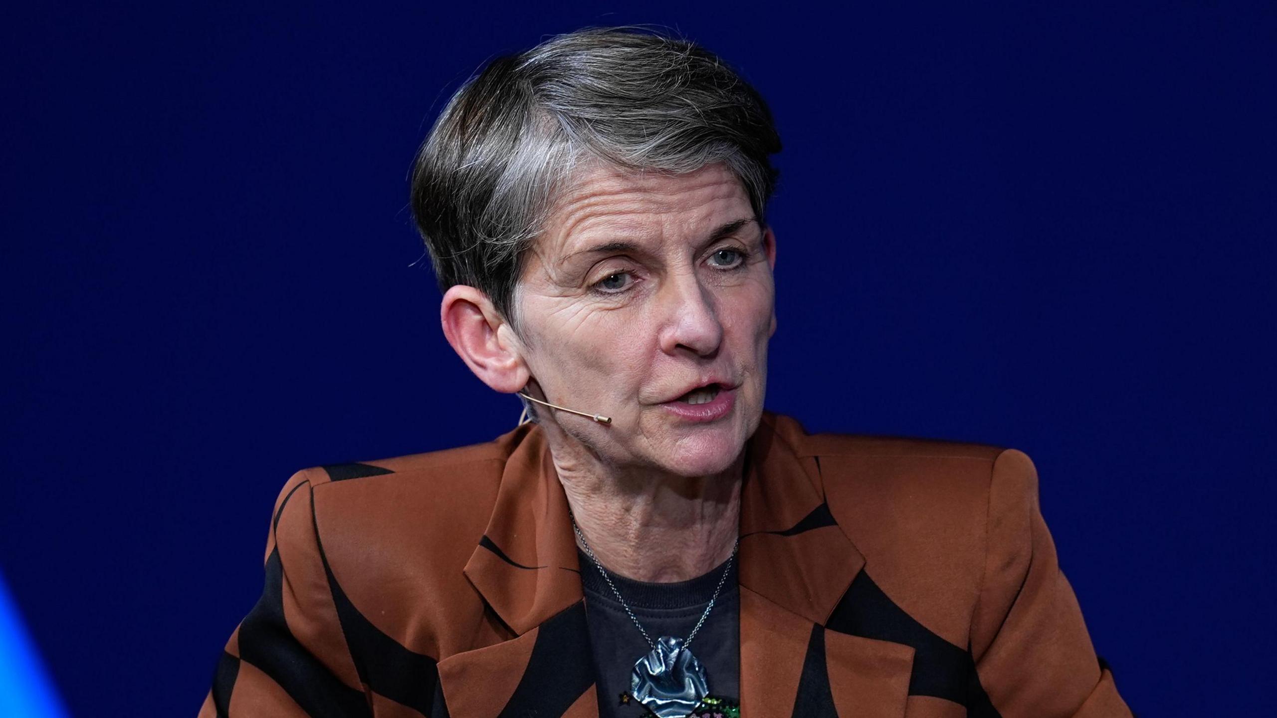 Laura McAllister speaking on a panel, wearing a hands-free microphone
