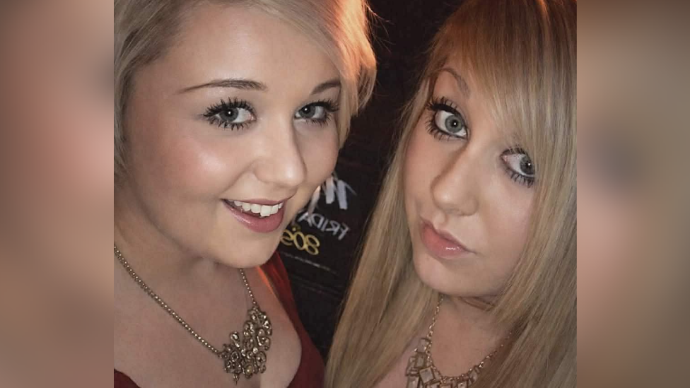 A selfie photo of two blonde girls wearing glitzy necklaces and low cut tops. They are both wearing lots of make up and smiling at the camera.