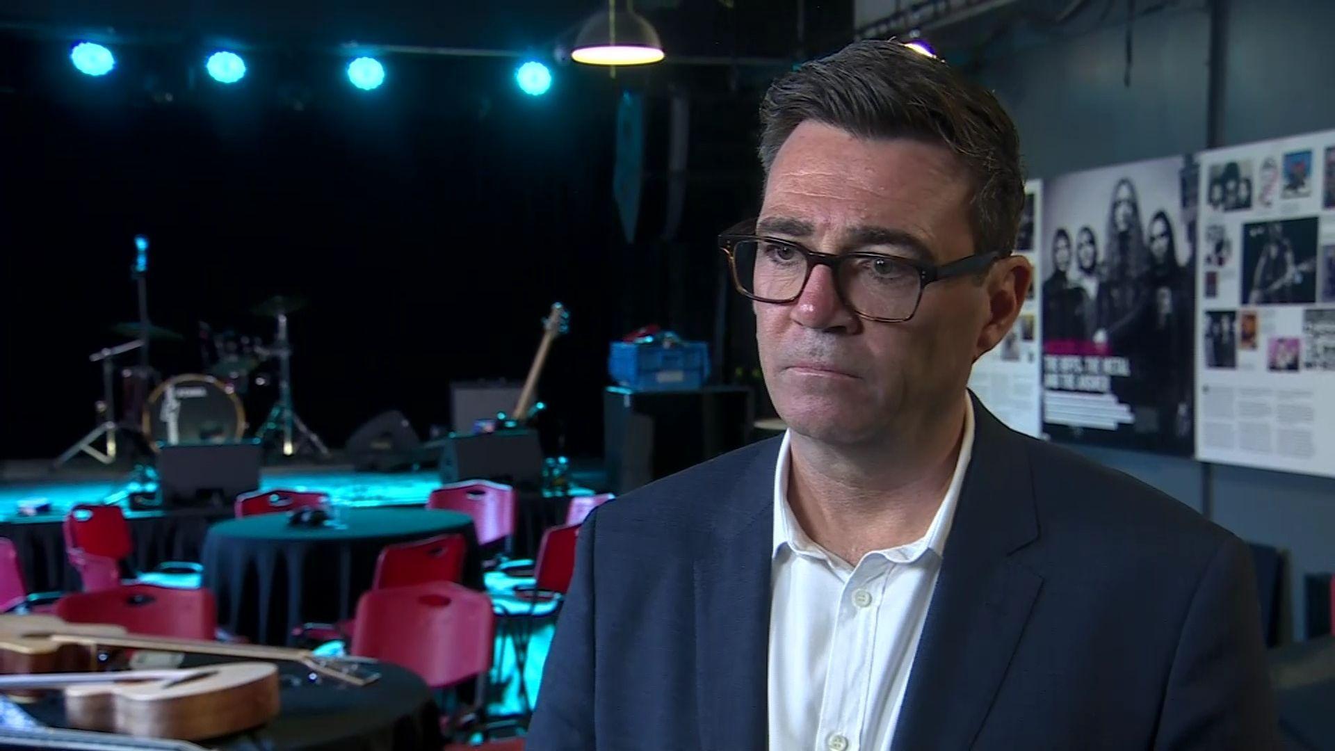 Andy Burnham. He has dark hair, wearing glasses, a navy blazer and white shirt.