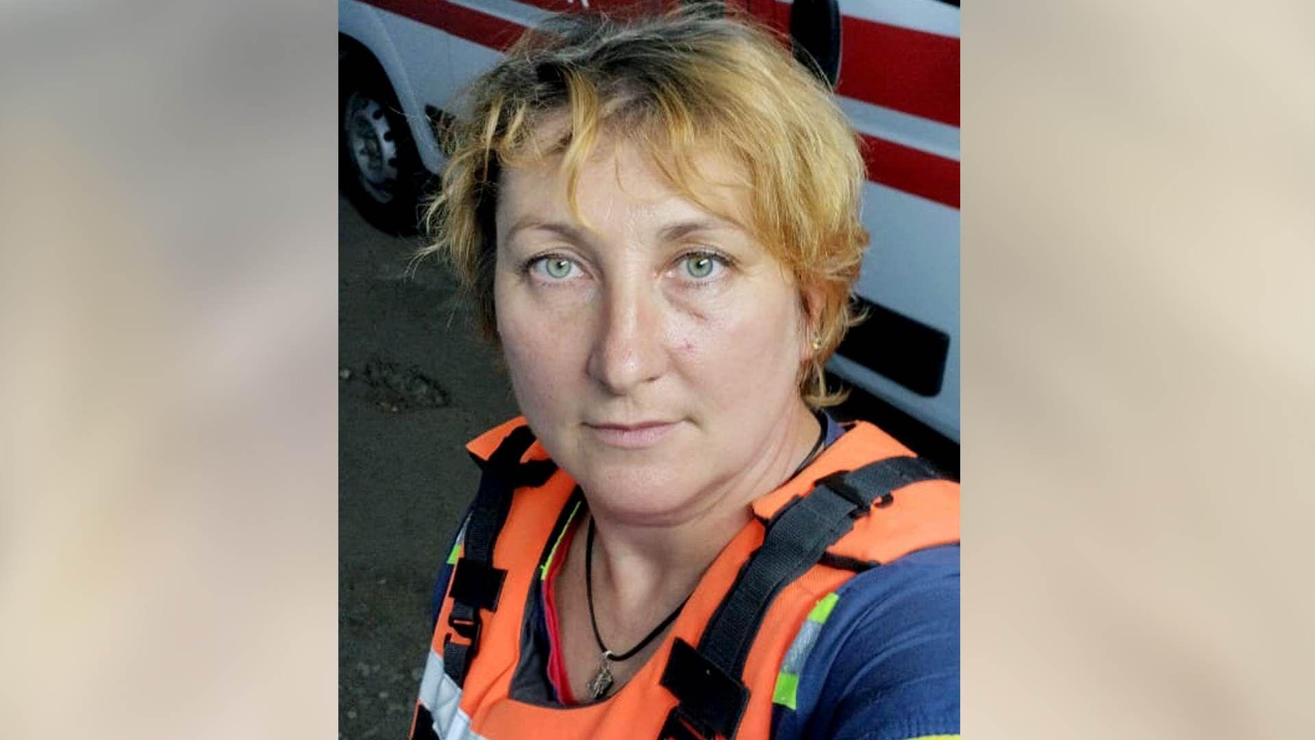 Inna Lytvynenko is wearing her bright orange body armour and standing in front of an ambulance.
