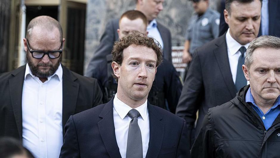 Mark Zuckerberg, wearing a navy suit and grey tie, leaving court in Los Angeles in February, flanked other personnel.