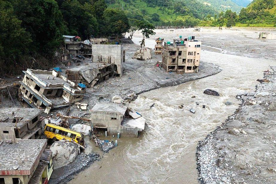 A Muddy Trishuli River surging past collapsing houses after flash floods in Nuwakot, Nepal