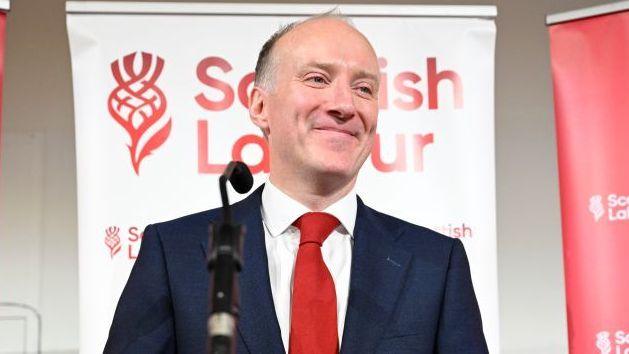 Michael Marra smiling on stage after his election