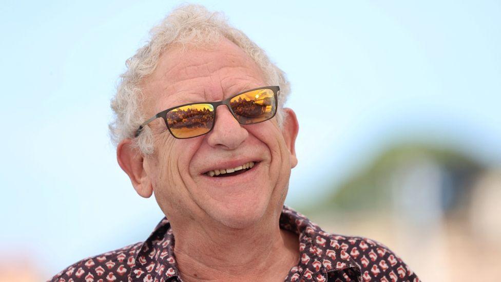 Jeremy Thomas smiling in orange tinted sunglasses and a shirt at the Cannes Film Festival in 2021