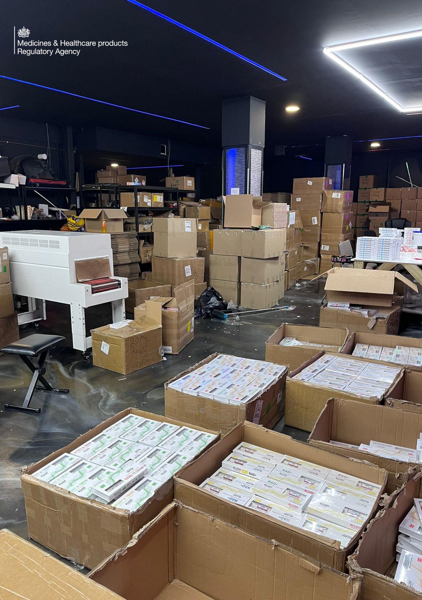 An interior shot of a factory showing boxes of drugs. Cardboard boxes are open showing unlicensed medication in little white boxes