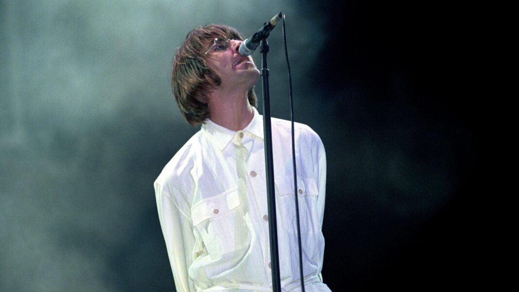 Oasis add shows in Knebworth, Rome and Munich Liam Gallagher, dressed in white, is lurching into a microphone on a stand as he performs at Knebworth.