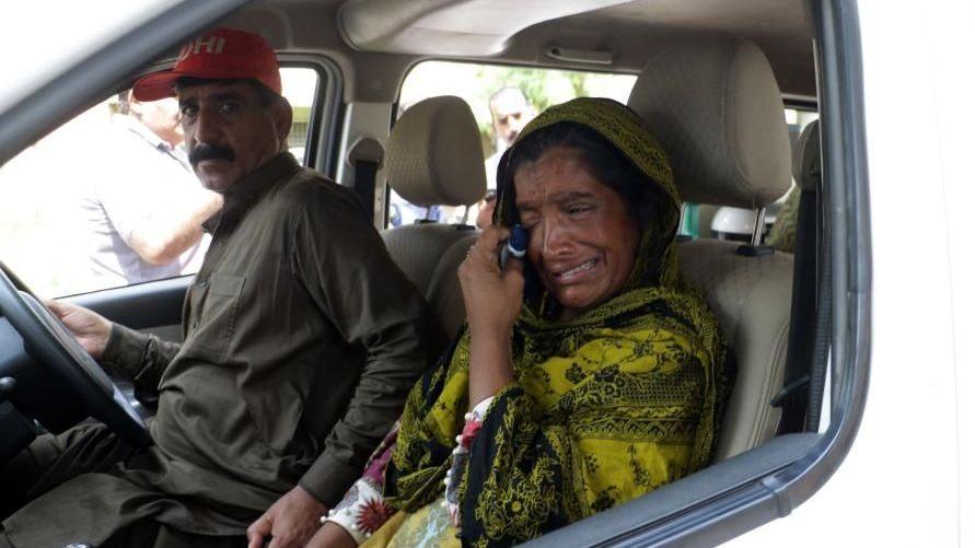 A woman sitting in a car, cying and wiping tears from her face.