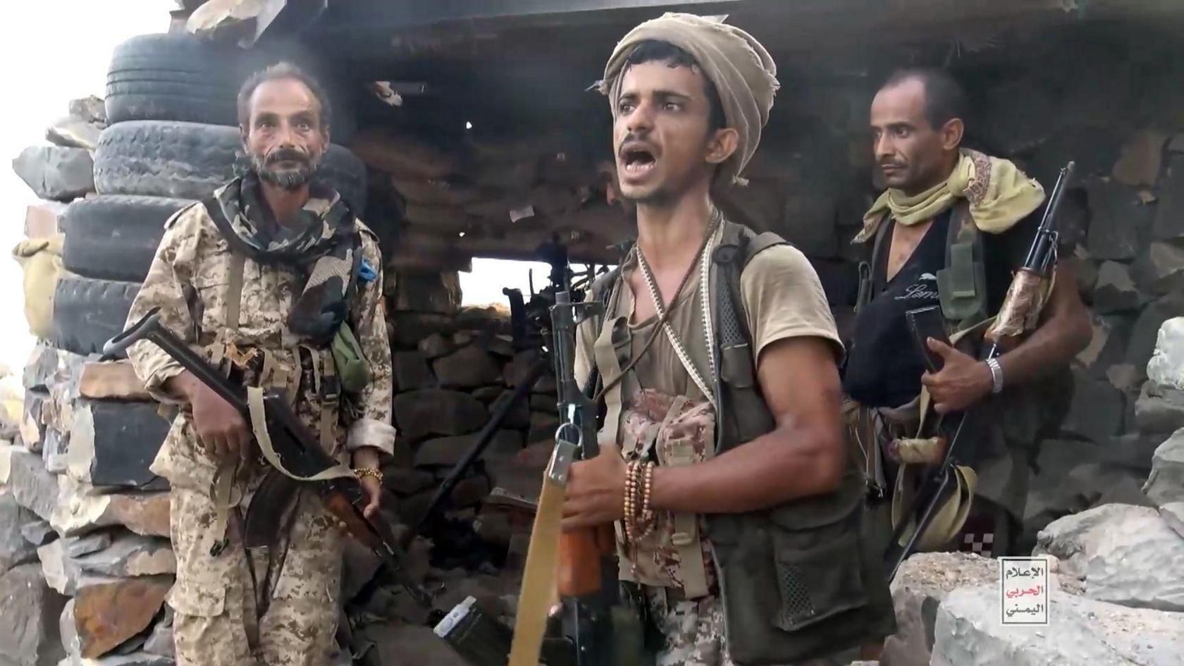 Houthi fighters at a seized camp in Mokha during their recent advance - three men stand in fighting gear with automatic weapons in an improvised fortified position