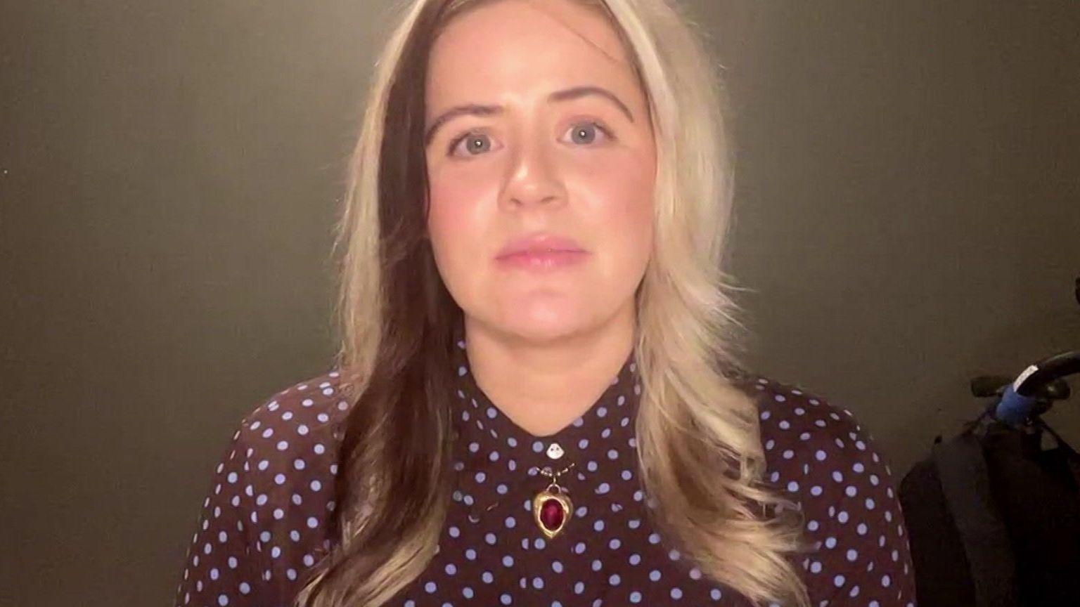 A woman with long light blonde hair with a dark front section faces the camera.