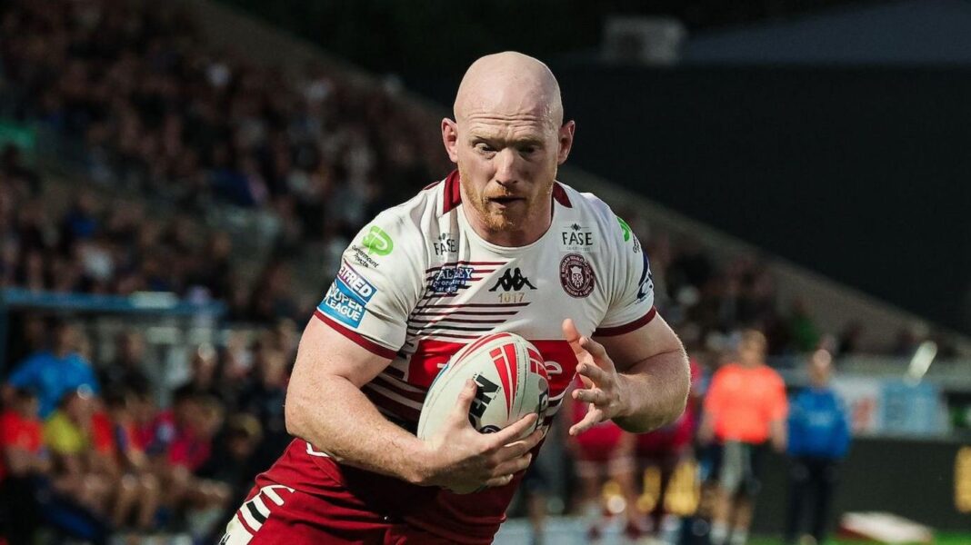 Liam Farrell scoring a try with the ball in his right hand for Wigan