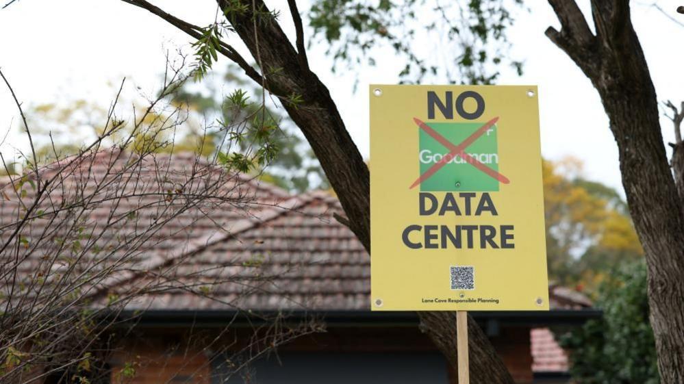 A yellow placard reading 'No data centre' in front of a house and trees