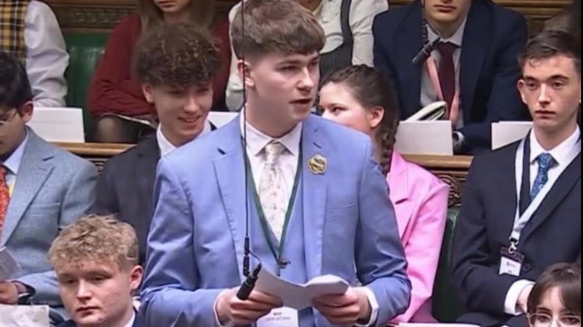 A young man in a light blue suit speaks in the House of Commons.