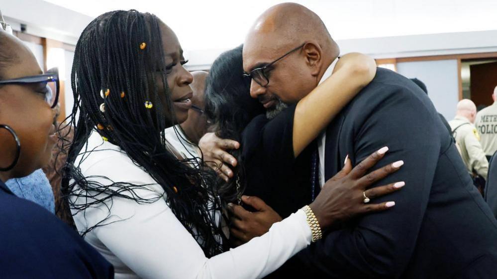 Friends and family members of rapper Tupac Shakur, including his sister Sekyiwa Shakur, line up to hug Chief Deputy District Attorney Binu Palal