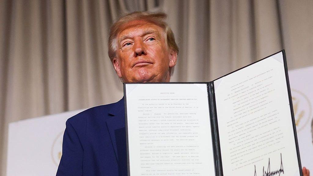 Donald Trump holding a leather-bound executive order at the launch of America.gov on Tuesday, 29 September.