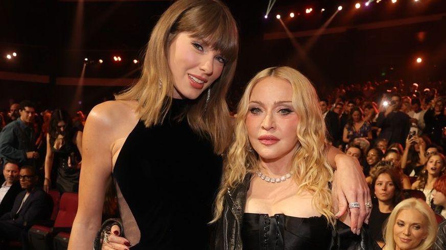 Taylor Swift and Madonna embrace while looking into the camera at the MTV VMA awards as the audience looks on