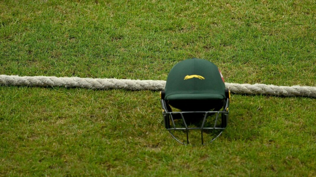 A green Leicestershire team helmet on the ground next to the boundary rope